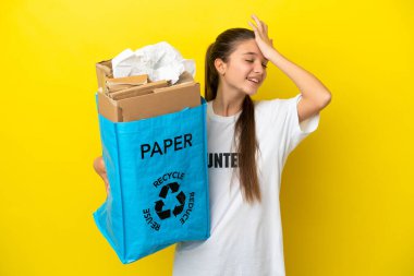 Sarı arka plan üzerinde geri dönüşüm yapmak için kağıt dolu bir geri dönüşüm çantası tutan küçük kız bir şey fark etti ve çözümü amaçladı.