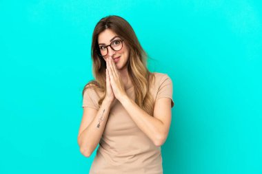 Mavi arka planda izole edilmiş genç beyaz kadın avuç içlerini bir arada tutuyor. İnsan bir şey ister.