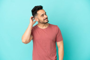 Kafkasyalı genç bir adam mavi arka planda izole edilmiş bir fikir düşünüyor.