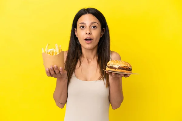 Young Caucasian Woman Holding Burger Chips Isolated Yellow Background — Stock Photo, Image