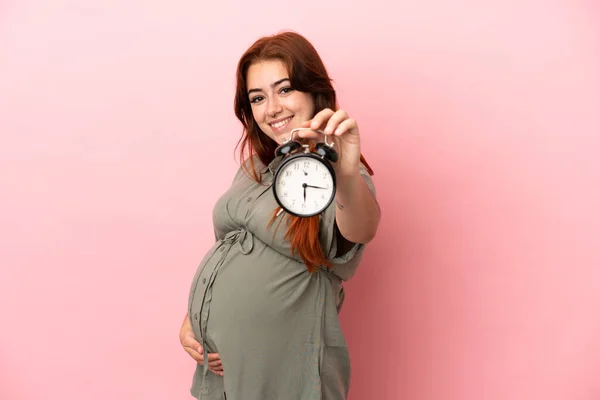 Jong Roodharige Blanke Vrouw Geïsoleerd Roze Achtergrond Zwanger Houden Klok — Stockfoto