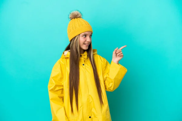 Niña Usando Una Capa Impermeable Sobre Fondo Azul Aislado Apuntando —  Fotos de Stock