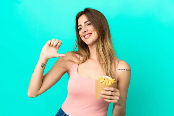 Mujer Caucásica Sosteniendo Chips Fritos Aislados Sobre Fondo Azul Orgulloso — Foto de Stock