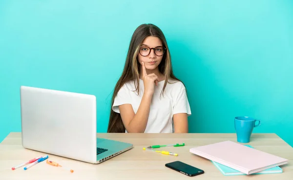 Menina Uma Mesa Com Laptop Sobre Fundo Azul Isolado Pensando — Fotografia de Stock