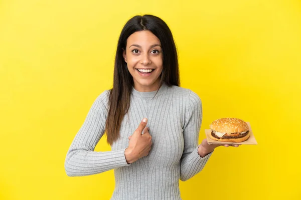 Young Caucasian Woman Holding Burger Isolated Yellow Background Surprise Facial — Stock Photo, Image