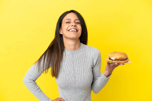 Young Caucasian Woman Holding Burger Isolated Yellow Background Posing Arms — Stock Photo, Image