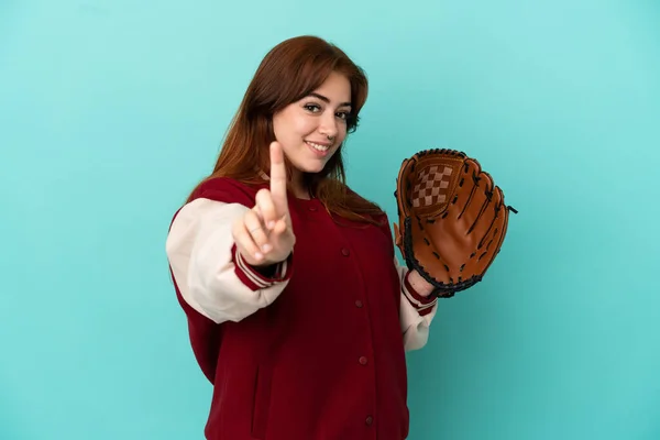 若いです赤毛女性遊ぶ野球の孤立した青の背景ショーと持ち上げる指 — ストック写真