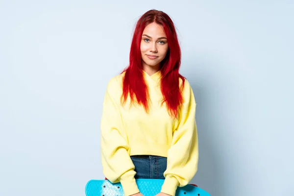 年轻的红头发女孩 带着溜冰鞋 与蓝色背景隔离在一起 — 图库照片