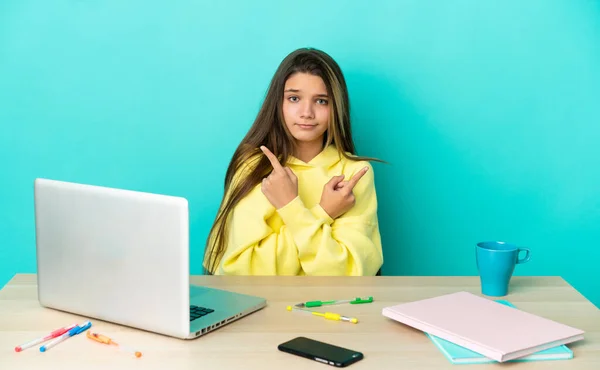 Niña Una Mesa Con Portátil Sobre Fondo Azul Aislado Apuntando — Foto de Stock