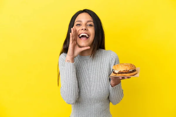 Young Caucasian Woman Holding Burger Isolated Yellow Background Shouting Mouth — Stock Photo, Image