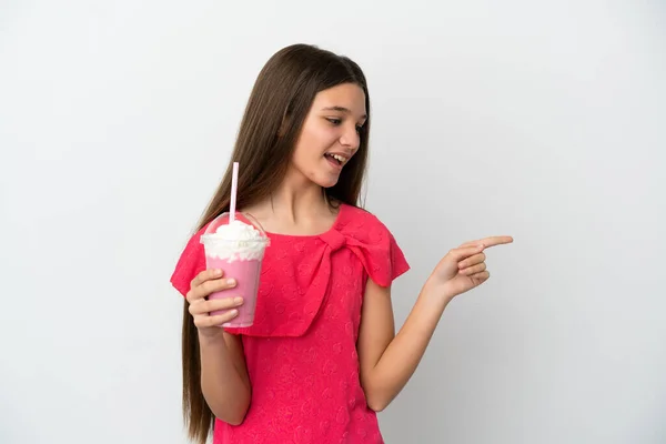小さな女の子とともにイチゴミルクセーキ上の隔離された白い背景指差し指に側面と製品を提示 — ストック写真