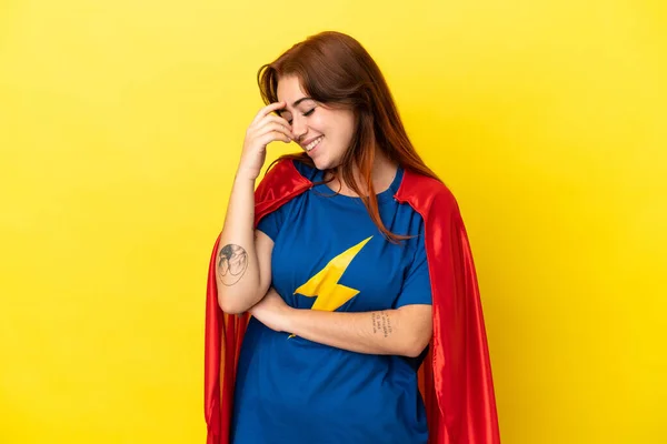 Super Hero redhead woman isolated on yellow background laughing
