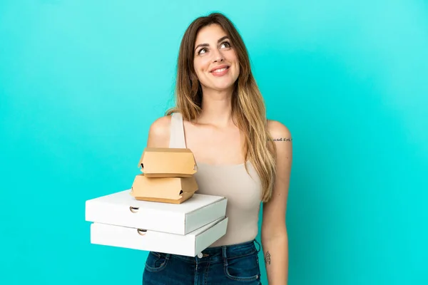 Kaukasische Frau Hält Pizzen Und Burger Isoliert Auf Blauem Hintergrund — Stockfoto