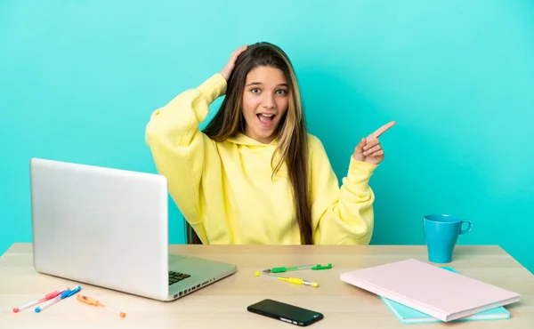 Menina Uma Mesa Com Laptop Sobre Fundo Azul Isolado Surpreendido — Fotografia de Stock