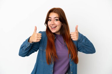 Beyaz arka planda izole edilmiş genç, kızıl saçlı bir kadın baş parmak işareti yapıyor.
