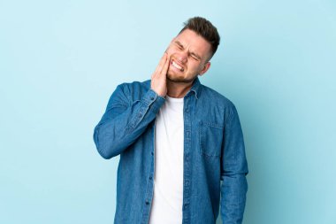 Rus yakışıklı adam mavi arka planda diş ağrısı çekiyor.