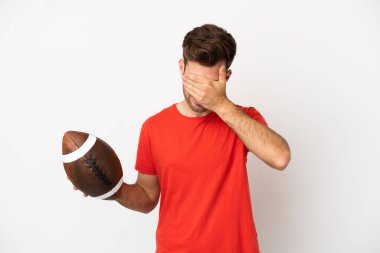 Beyaz arka planda ragbi oynayan genç beyaz bir adam yorgun ve hasta bir ifadeyle izole edilmiş.