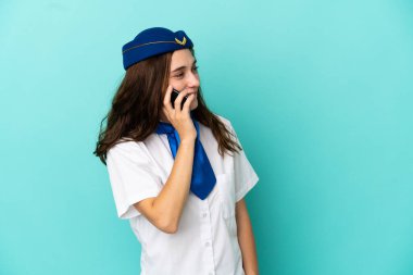 Uçak hostesi kadın mavi arka planda izole edilmiş cep telefonuyla birileriyle sohbet ediyor.