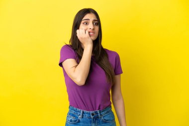 Sarı arka planda izole edilmiş genç beyaz kadın biraz gergin.
