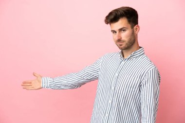 Pembe arka planda soyutlanmış beyaz tenli yakışıklı adam davet edildiği için ellerini yana uzatıyor.