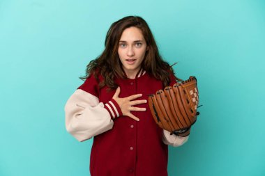 Beyzbol oynayan beyaz bir kadın mavi arka planda izole edilmiş, sağa bakarken şaşırmış ve şok olmuştu.