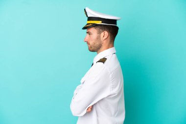 Kafkasyalı uçak pilotu mavi arka planda yan pozisyonda izole edildi.
