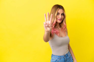 Soyutlanmış sarı arka plan mutlu ve parmaklarıyla üçe kadar sayıyor.