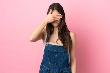 Pembe arka planda izole edilmiş, gözleri elle kaplanmış beyaz bir kadın. Bir şey görmek istemiyorum.