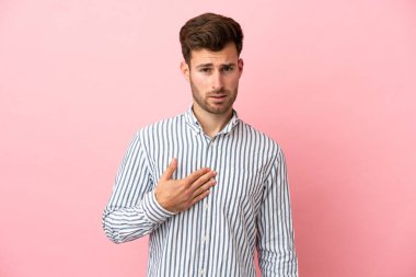 Pembe arka planda izole edilmiş beyaz tenli yakışıklı bir adam kendini işaret ediyor.