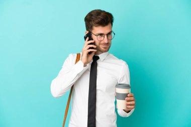 İş adamı izole edilmiş arka planda kahve ve cep telefonu tutuyor.