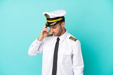 Kafkasyalı uçak pilotu mavi arka planda izole bir şekilde gülüyor.