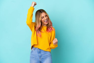 Genç bir kadın mavi arka planda zaferi kutluyor.