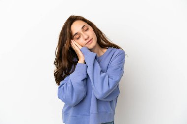 Beyaz arka planda izole edilmiş genç beyaz kadın uyku jesti yapıyor.