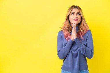 İzole edilmiş sarı arka plandaki genç kadın avuç içlerini bir arada tutuyor. İnsan bir şey ister.