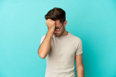 Kafkasyalı yakışıklı genç adam mavi arka planda başağrısı ile izole edilmiş.