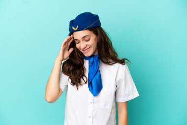 Uçak hostesi kadın mavi arka planda izole edilmiş gülüyor.