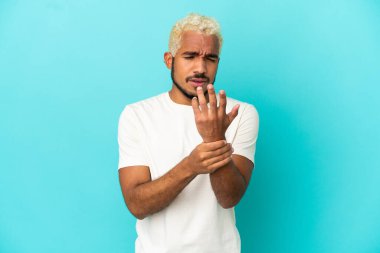 Genç Kolombiyalı yakışıklı adam mavi arka planda izole edildi.