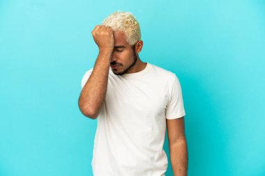 Genç Kolombiyalı yakışıklı adam mavi arka planda başağrısı ile izole