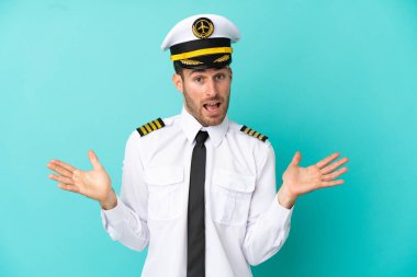 Kafkasyalı uçak pilotu mavi arka planda şok olmuş yüz ifadesiyle izole edildi.