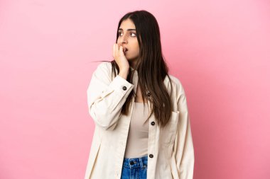 Pembe arka planda izole edilmiş genç beyaz kadın biraz gergin.