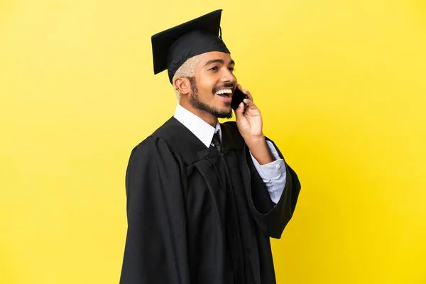 Junger Kolumbianischer Universitätsabsolvent Isoliert Auf Gelbem Hintergrund Und Hält Ein — Stockfoto