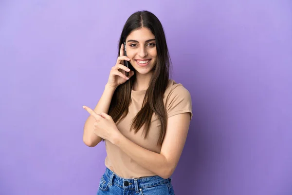 Молодая Кавказская Женщина Используя Мобильный Телефон Изолирован Фиолетовом Фоне Указывая — стоковое фото