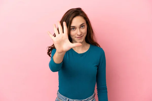 ピンクの背景に5本指で数える若い白人女性 — ストック写真
