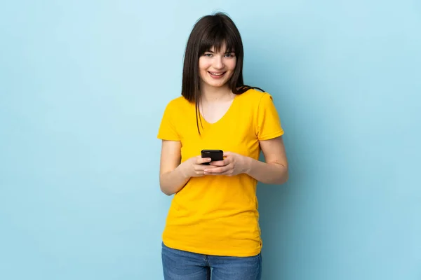 Adolescente Ucraniana Chica Aislada Fondo Azul Enviando Mensaje Con Móvil —  Fotos de Stock