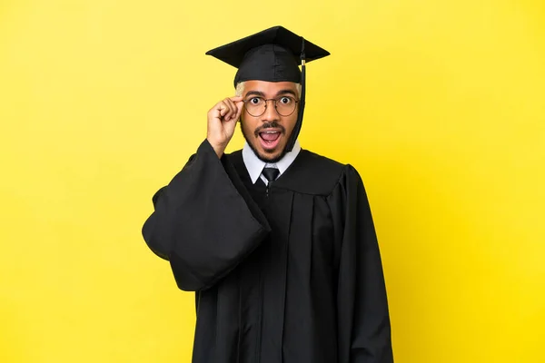 Joven Graduado Universitario Colombiano Aislado Sobre Fondo Amarillo Con Gafas —  Fotos de Stock