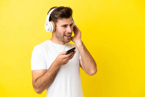 Νεαρός Καυκάσιος Όμορφος Άνδρας Απομονωμένος Κίτρινο Φόντο Ακούγοντας Μουσική Κινητό — Φωτογραφία Αρχείου