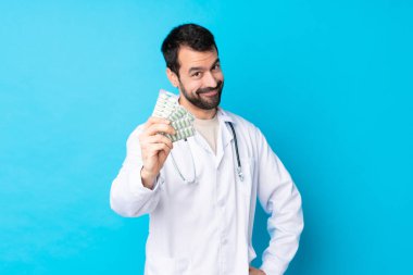 Kafkas kökenli genç bir adam. Doktor önlüğü giyiyor ve elinde haplar var.