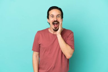 Mavi arka planda mahsur kalmış, şaşırmış ve şok olmuş genç bir beyaz adam.