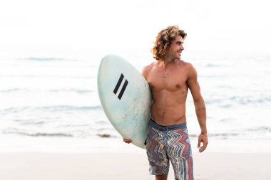 Kafkasyalı genç adam gün doğumunda sörf yapmak için erken kalkar.