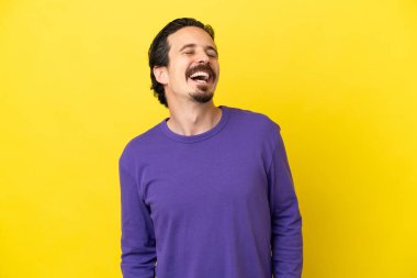Sarı arka planda izole edilmiş genç beyaz adam gülüyor.